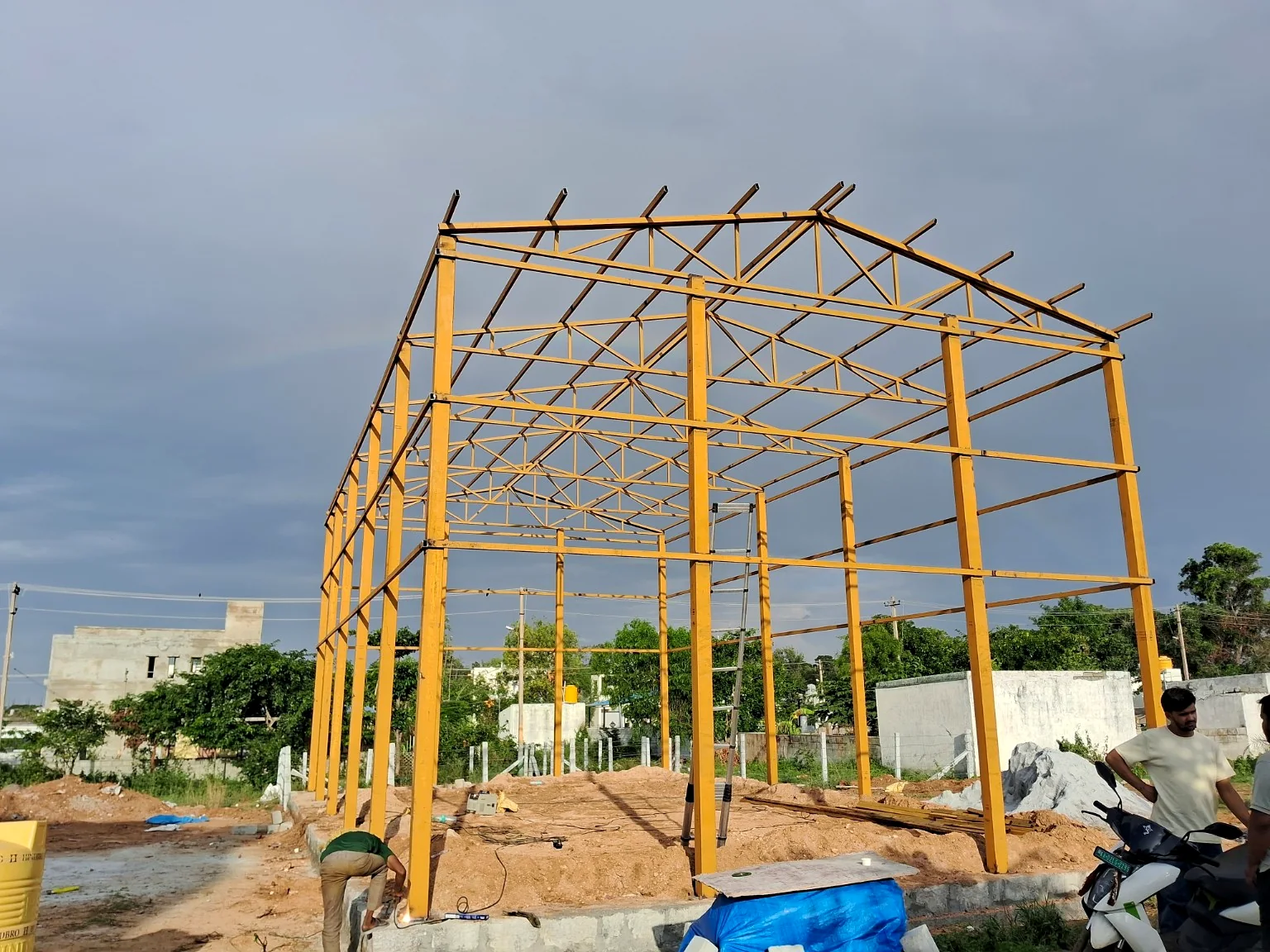 Fabricated yellow steel columns and roof framing for an industrial structure.