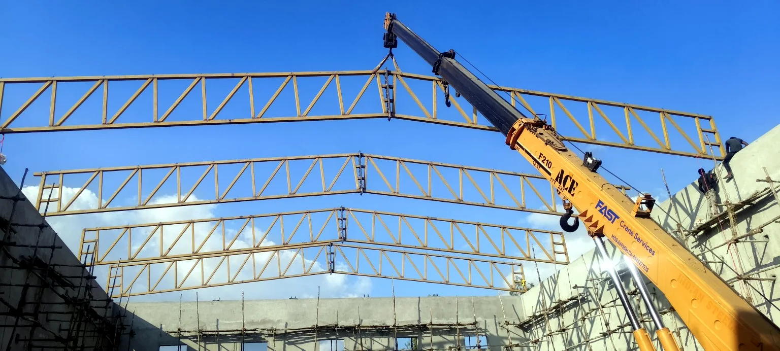 Mobile crane lifting and positioning a long-span roof truss.