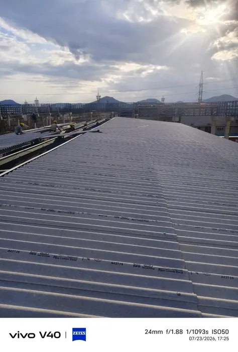 Industrial roofing installation in progress over a long-span steel structure.