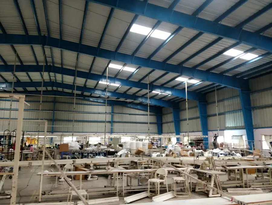 Factory shed interior with portal steel frame, roofing and industrial workspace.