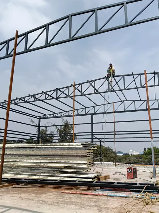 Steel roof trusses and purlins being installed at height.