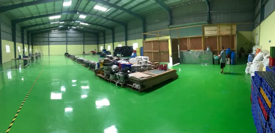 Completed industrial floor with green epoxy finish inside a fabricated structure.