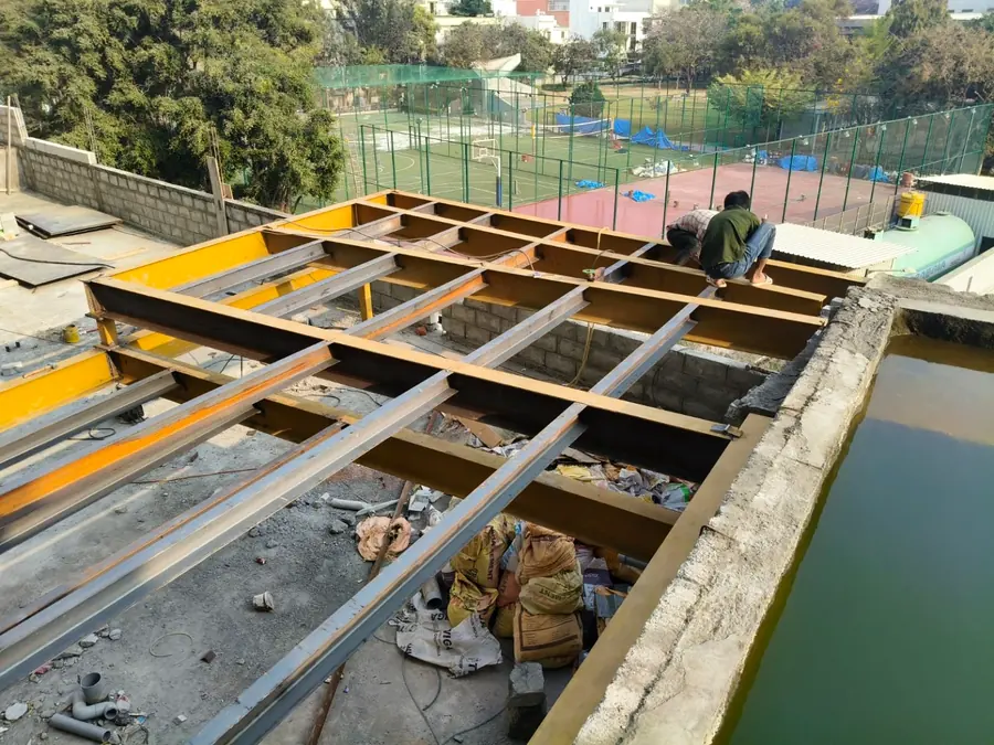 Heavy structural steel floor beams being assembled on a rooftop project.
