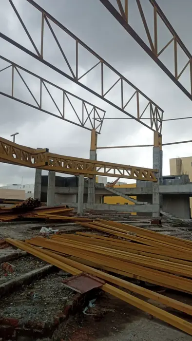 Roof truss erection over a concrete building using fabricated steel members.