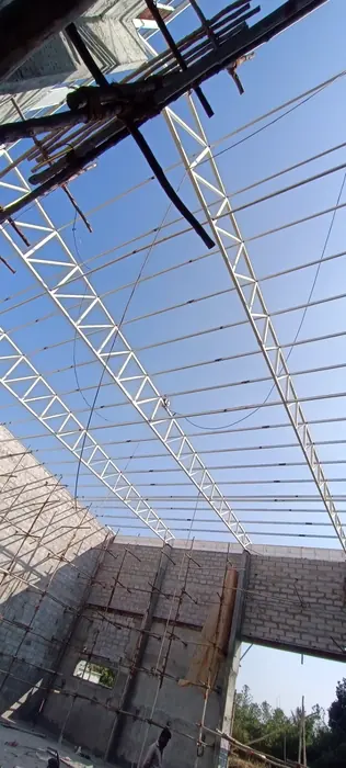White long-span light steel trusses and purlins inside a masonry shell.