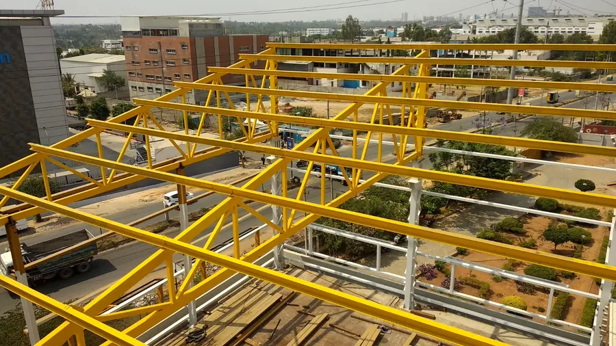 Yellow painted roof framing and truss members installed over a building.